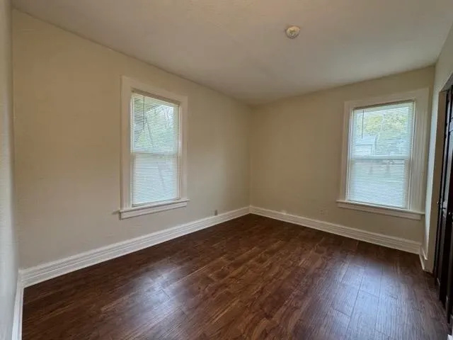 an empty room with wooden floor and windows