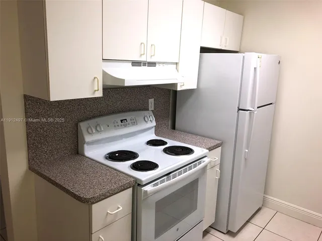 a kitchen with a sink a refrigerator and cabinets