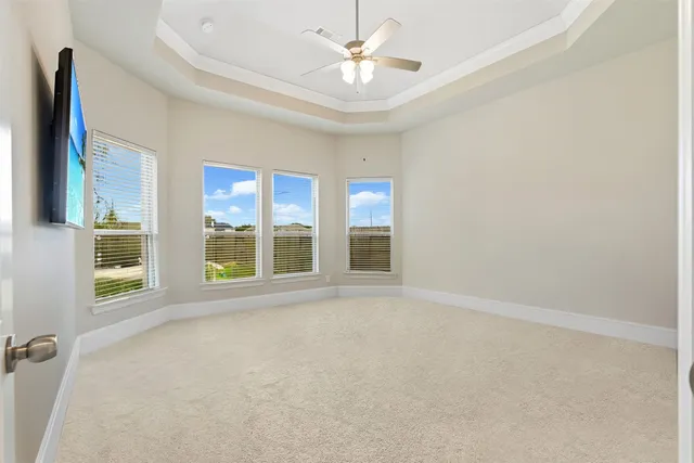 an empty room with chandelier fan and windows