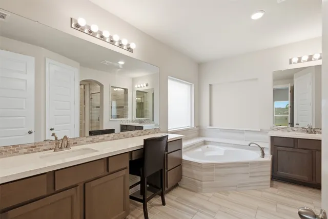 a spacious bathroom with a bathtub double sink and mirror