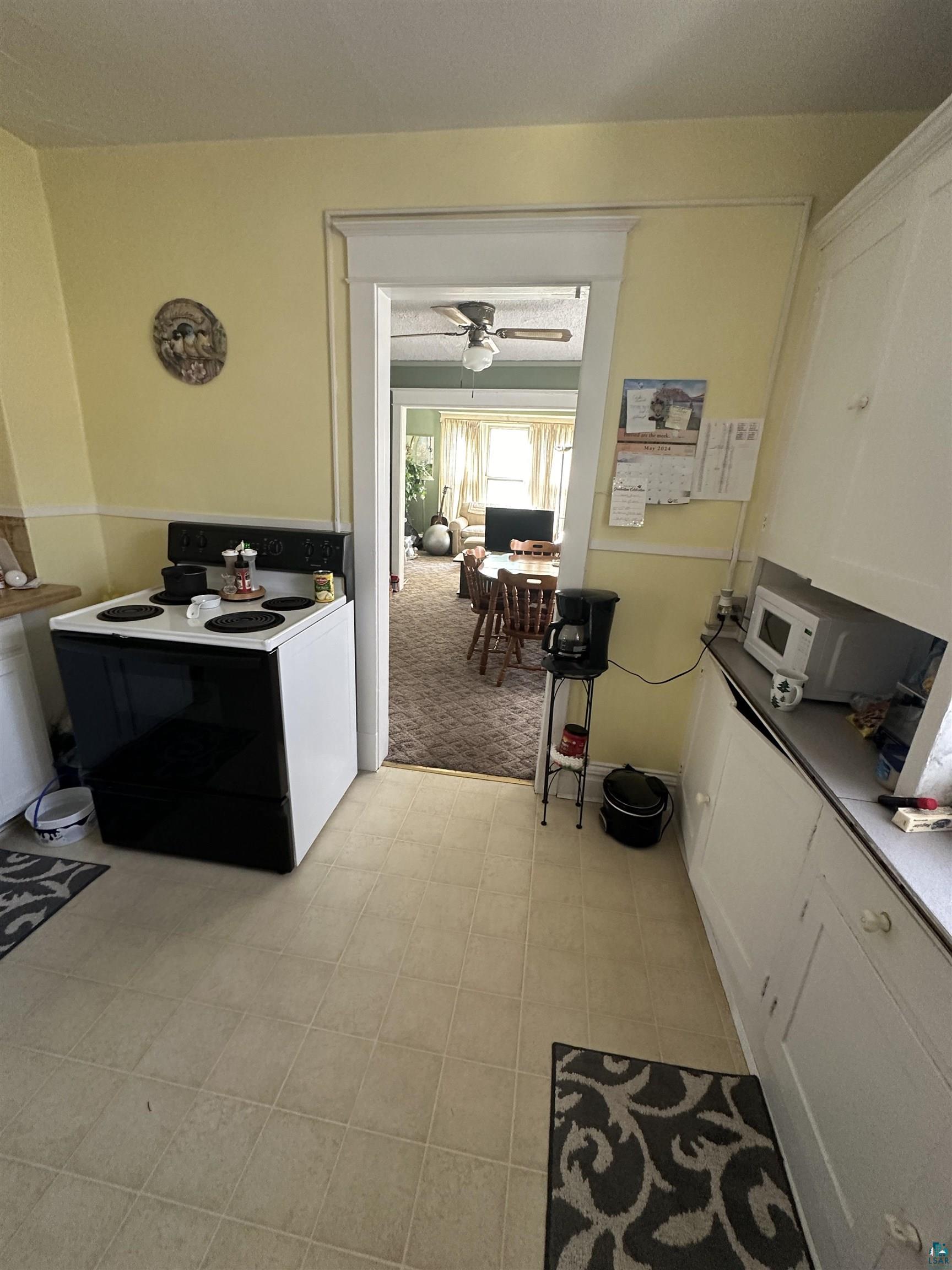 2119 West 3rd Street Duluth, MN 55806 - Photo 22 of 32 Kitchen featuring light carpet, white cabinetry, electric stove, and ceiling fan