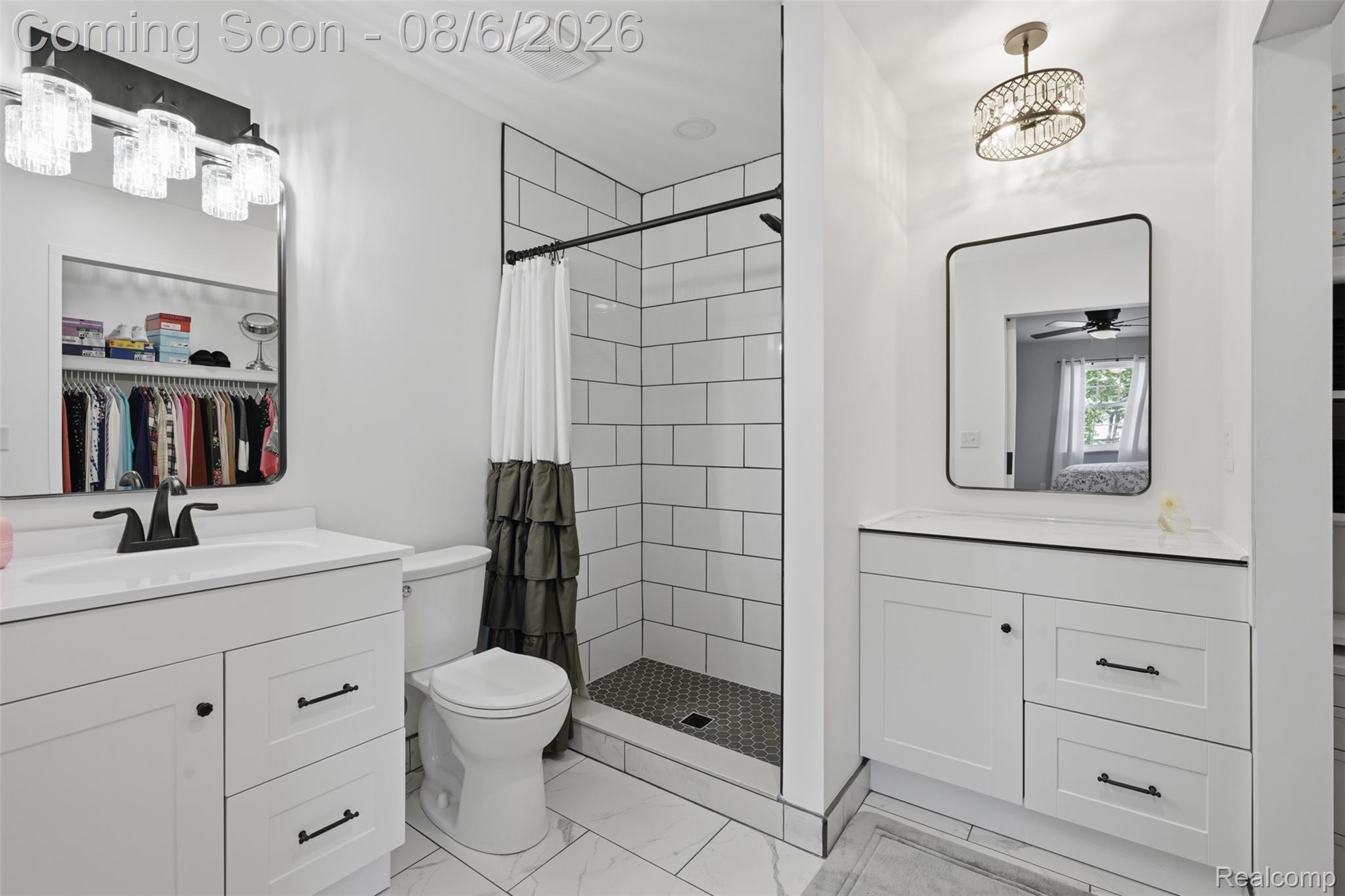 3585 Loon Lake Road Wixom, MI 48393 - Photo 15 of 40 Spa-inspired primary bathroom featuring dual vanities with white cabinetry and black hardware, framed mirrors with integrated lighting, a walk-in shower with subway tile surround and glass enclosure, and white ceramic tile flooring