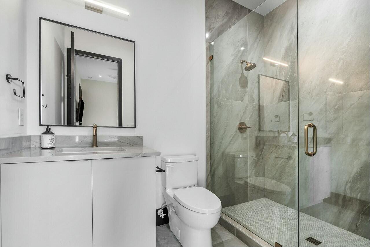 13480 Highway 1 Juno Beach, FL 33408 - Photo 50 of 90 a bathroom with a granite countertop toilet sink shower and mirror
