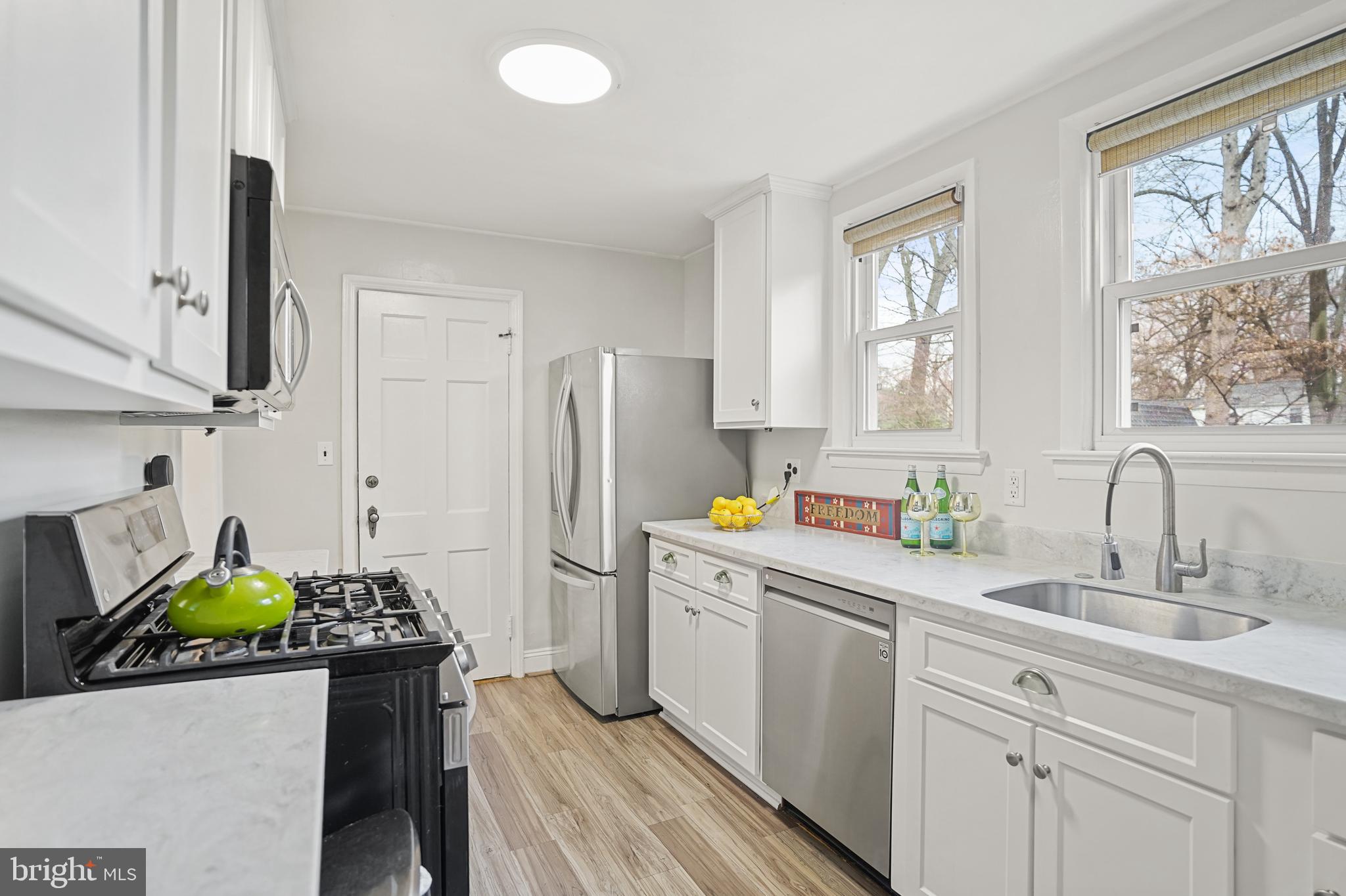 8907 Flower Avenue Silver Spring, MD 20901 - Photo 3 of 20 a kitchen with stainless steel appliances a sink a refrigerator cabinets and a window