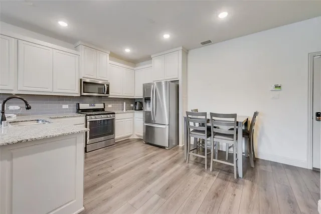 a kitchen with kitchen island granite countertop a sink a counter space appliances and cabinets