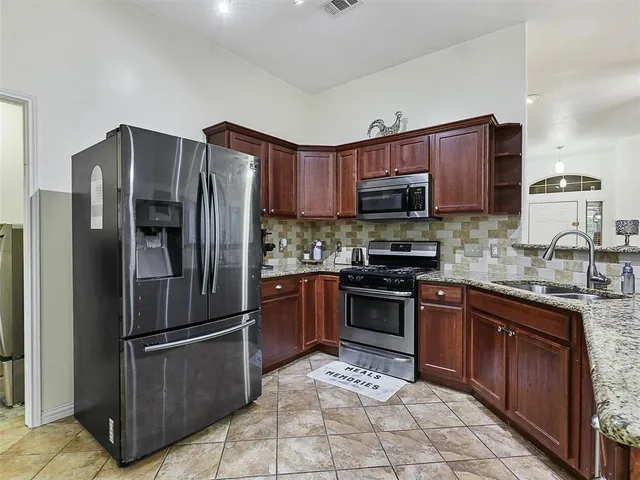 a kitchen with stainless steel appliances granite countertop a stove refrigerator and cabinets