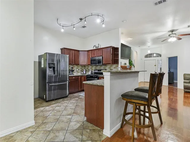 a kitchen with stainless steel appliances a refrigerator a stove a dining table and chairs with wooden floor