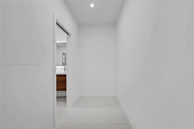 an empty room with chandelier fan and windows