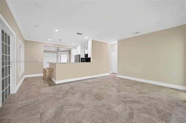 a view of an empty room with kitchen and a window