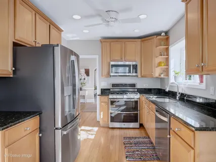 a kitchen with granite countertop stainless steel appliances a refrigerator stove top oven and sink