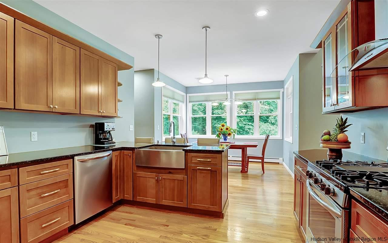 194 Harry Wells Road Saugerties, NY 12477 - Photo 17 of 35 a kitchen with stainless steel appliances granite countertop wooden cabinets a stove a sink a dining table and chairs with wooden floor