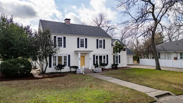 a view of a white house with a big yard and large tree