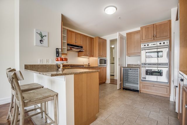 a kitchen with kitchen island granite countertop a stove top oven microwave and refrigerator