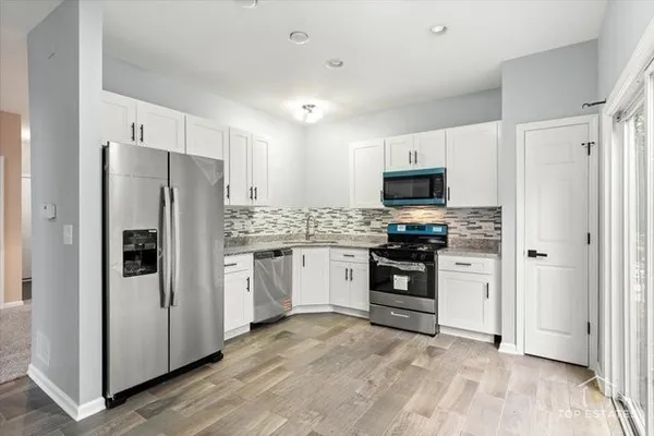 a kitchen with granite countertop a refrigerator and a stove top oven