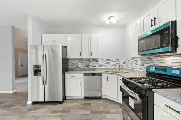 a kitchen with stainless steel appliances granite countertop a stove a refrigerator and a microwave
