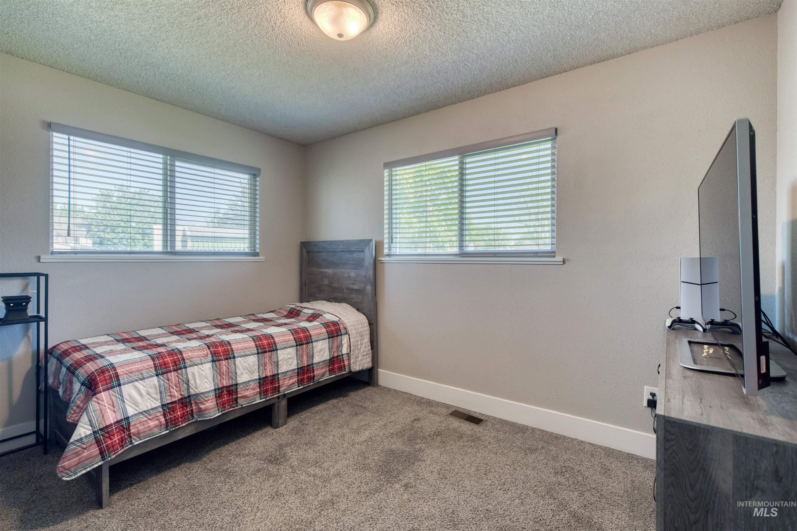 20803 Friends Road Greenleaf, ID 83626 - Photo 18 of 39 Light-colored walls and carpet flooring define this room, featuring two windows with horizontal blinds and a flush-mount ceiling light