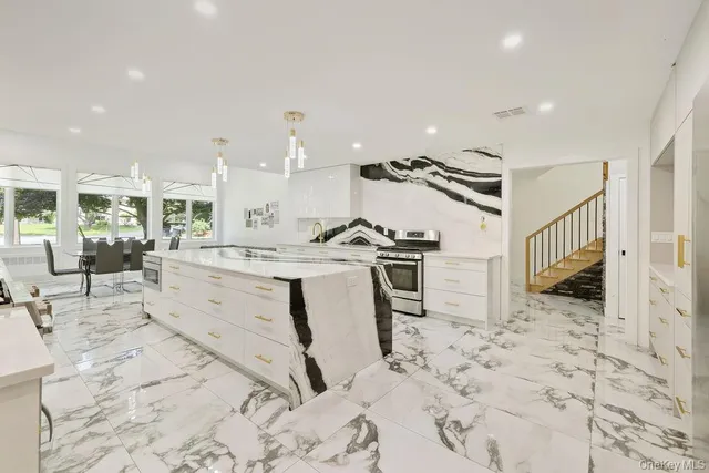 a view of a kitchen with kitchen island stainless steel appliances a stove a sink a window and counter space