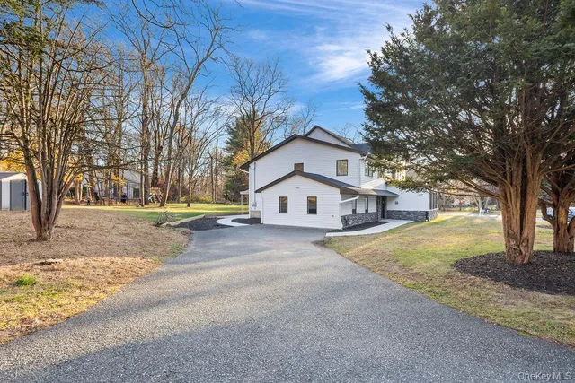 a front view of a house with a yard and tree s