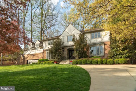 a front view of a house with a garden and trees