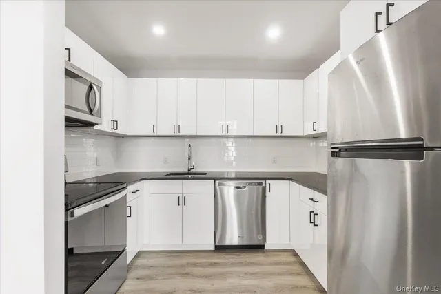 a kitchen with stainless steel appliances granite countertop a refrigerator and white cabinets
