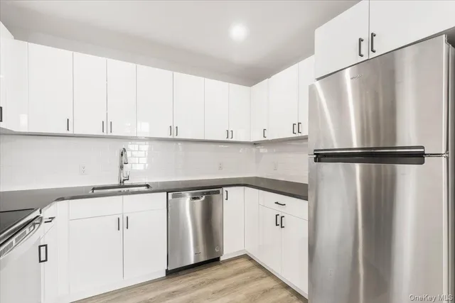 a kitchen with white cabinets and refrigerator