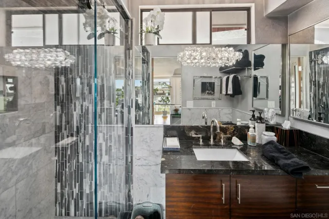 a bathroom with a granite countertop sink a mirror and shower