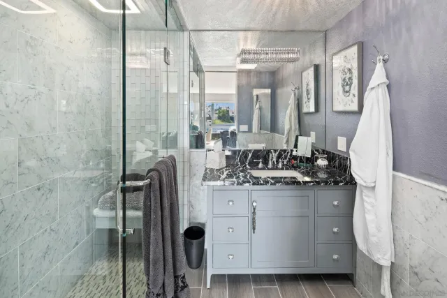 a bathroom with a granite countertop sink a mirror and shower