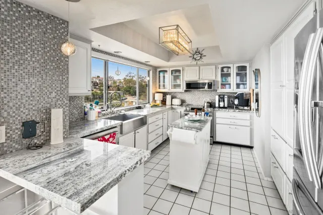 a open kitchen with stainless steel appliances granite countertop a stove a sink dishwasher and white cabinets with wooden floor