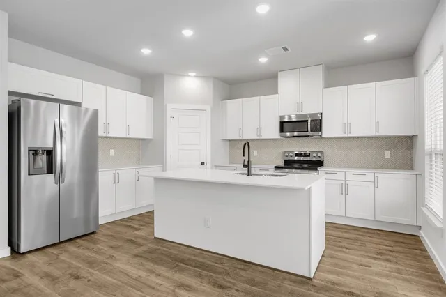 a kitchen with stainless steel appliances granite countertop a refrigerator sink and white cabinets