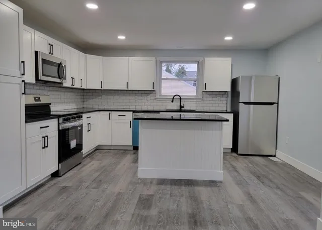 a kitchen with a sink a stove a refrigerator and white cabinets