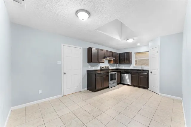 a large white kitchen with a stove top oven a sink and dishwasher