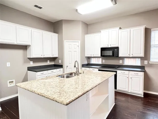 a kitchen with granite countertop a sink stove and microwave