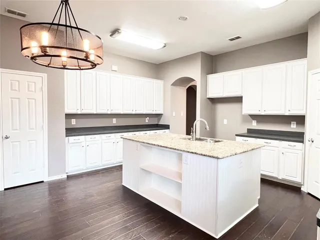 a kitchen with stainless steel appliances a chandelier and wooden floors