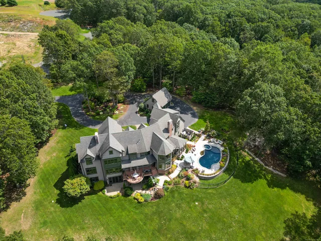 an aerial view of a house with swimming pool large trees and lawn chairs