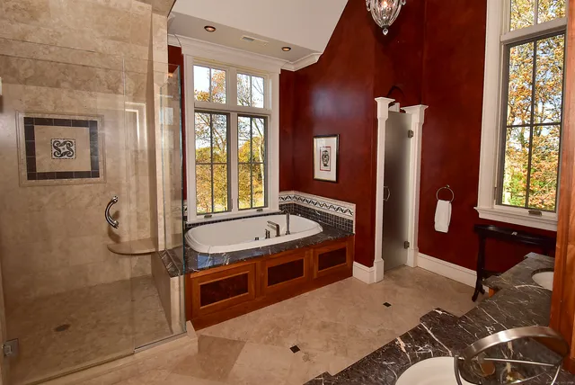 a bathroom with a tub a sink and glass windows