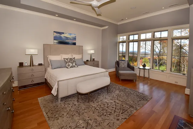 a bedroom with a large bed and a large window with rug