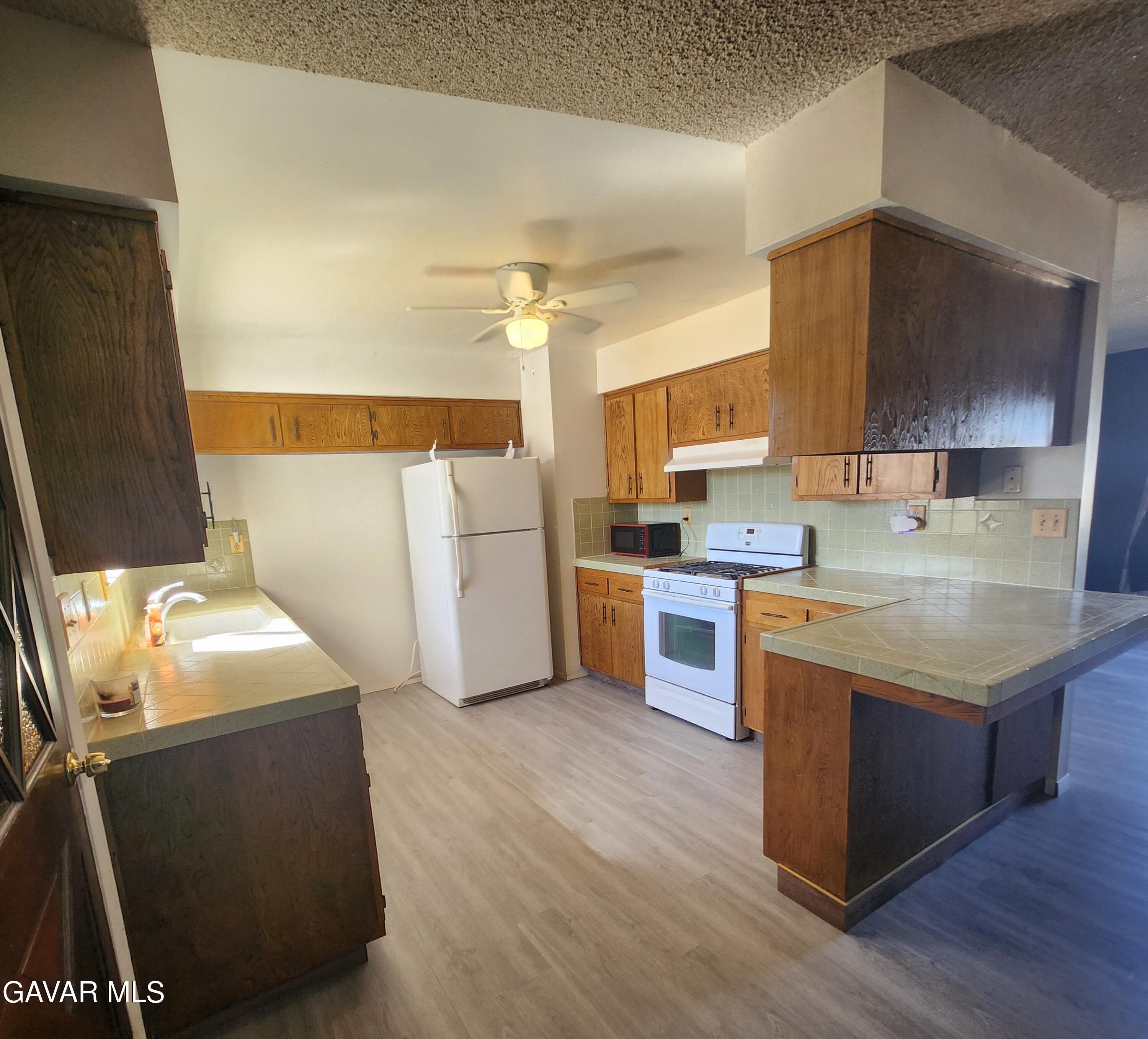 1407 West Burns Avenue Ridgecrest, CA 93555 - Photo 8 of 25 a kitchen with a sink a stove a refrigerator and a oven
