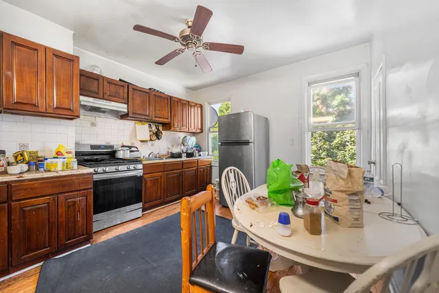 a kitchen with stainless steel appliances a stove a refrigerator a sink a dining table and chairs with wooden floor