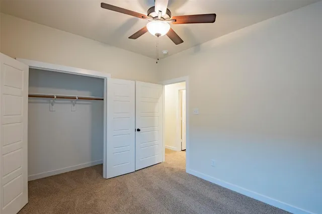 an empty room with closet and a chandelier fan