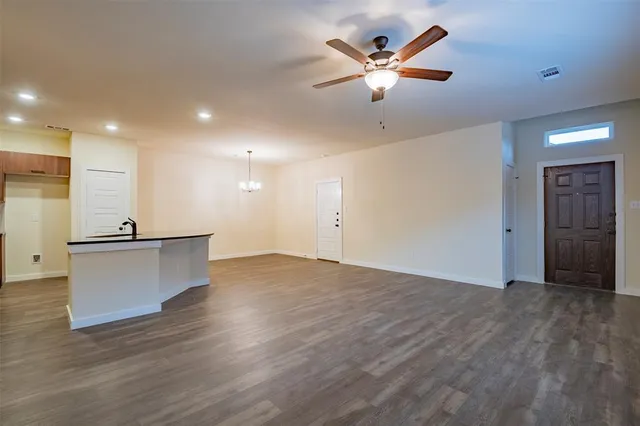 an empty room with wooden floor and a ceiling fan