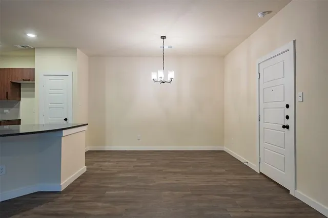 a view of an empty room with wooden floor and windows