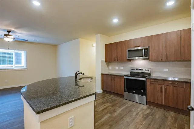 a kitchen with stainless steel appliances granite countertop a sink dishwasher stove and microwave with wooden floor