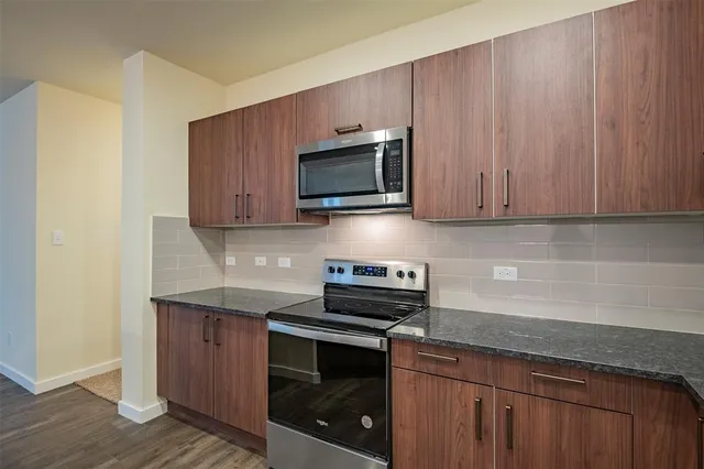 a kitchen with stainless steel appliances granite countertop wooden cabinets a stove a microwave and a sink