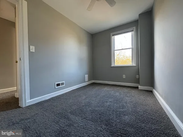 an empty room with a ceiling fan and a window
