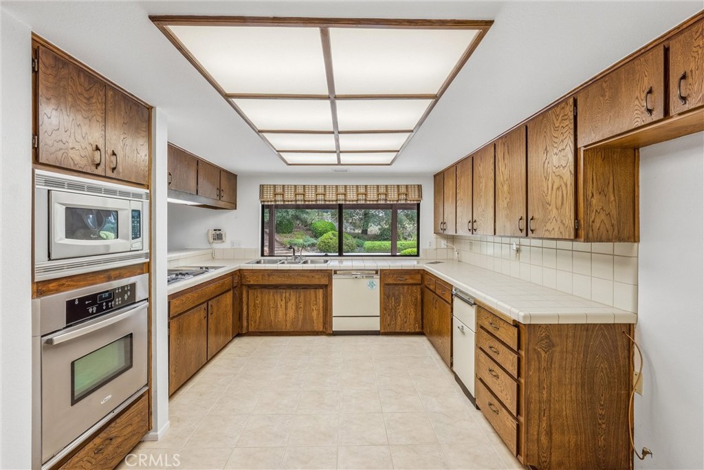 37295 Oak View Road Yucaipa, CA 92399 - Photo 13 of 59 a large kitchen with stainless steel appliances granite countertop a refrigerator a sink dishwasher a stove a dining table and chairs with wooden floor