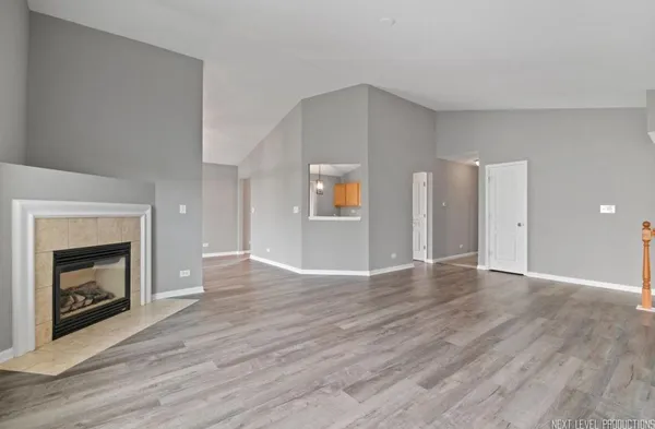a view of an empty room with wooden floor fireplace and a window