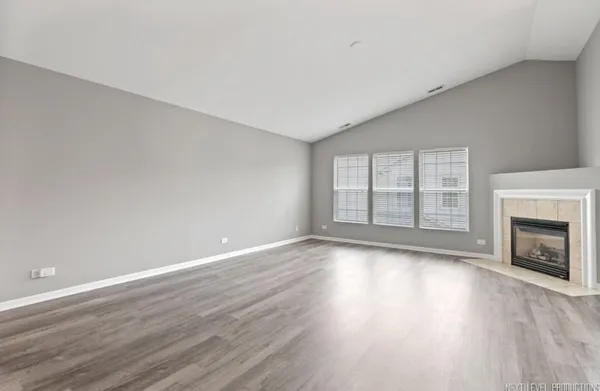 a view of an empty room with wooden floor fireplace and a window