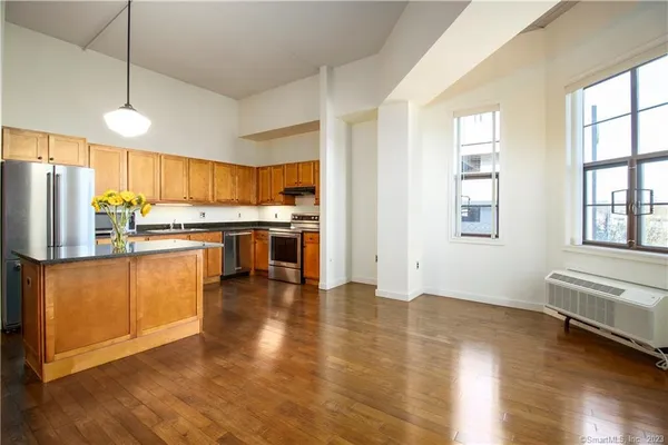 a kitchen with stainless steel appliances granite countertop a refrigerator a stove top oven a sink and dishwasher with wooden floor
