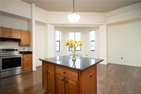 a kitchen with stainless steel appliances granite countertop a sink a stove and a wooden floors