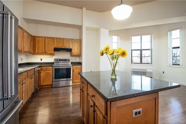 a kitchen with stainless steel appliances granite countertop a kitchen island a stove a sink cabinets and a dining table